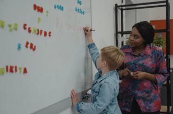 Teacher helping student at markerboard