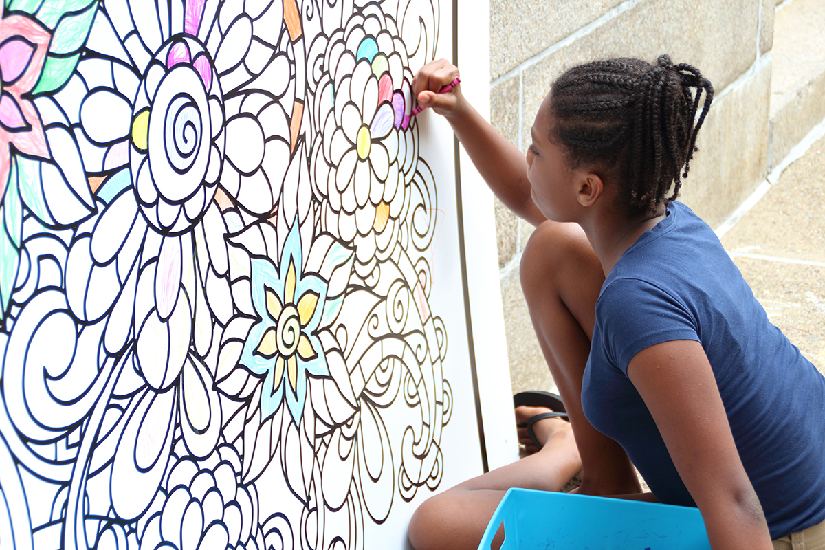Girl using crayons on mural-size coloring page