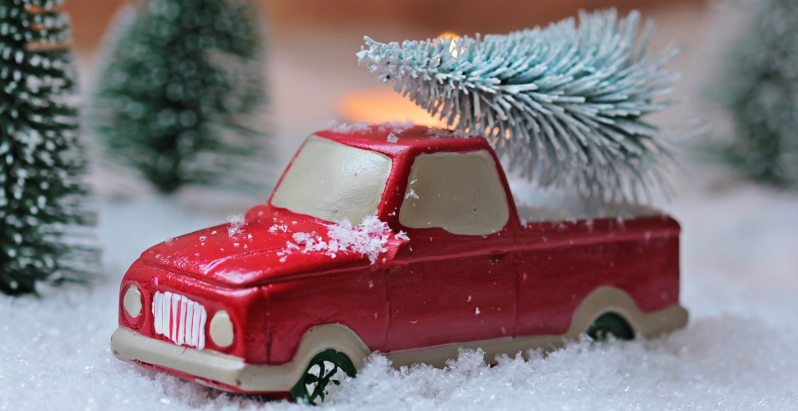 Small toy pickup truck in snow with wintry pine tree in bed of truck
