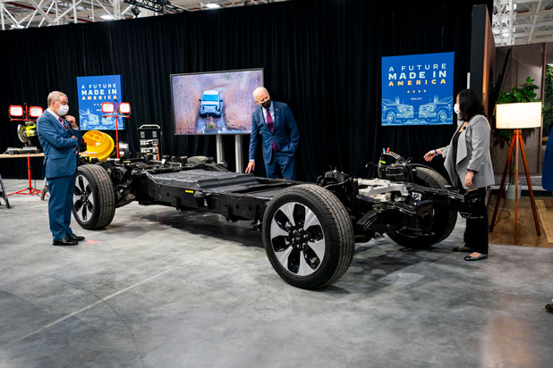 President Joe Biden stands next to a vehicle being manufactured