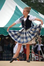 Young female Highland Dancer in green tartan in front of a green and white tent