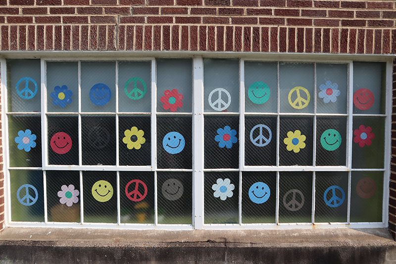 Clendenin Branch window display with colorful smiley faces, flowers, and peace signs