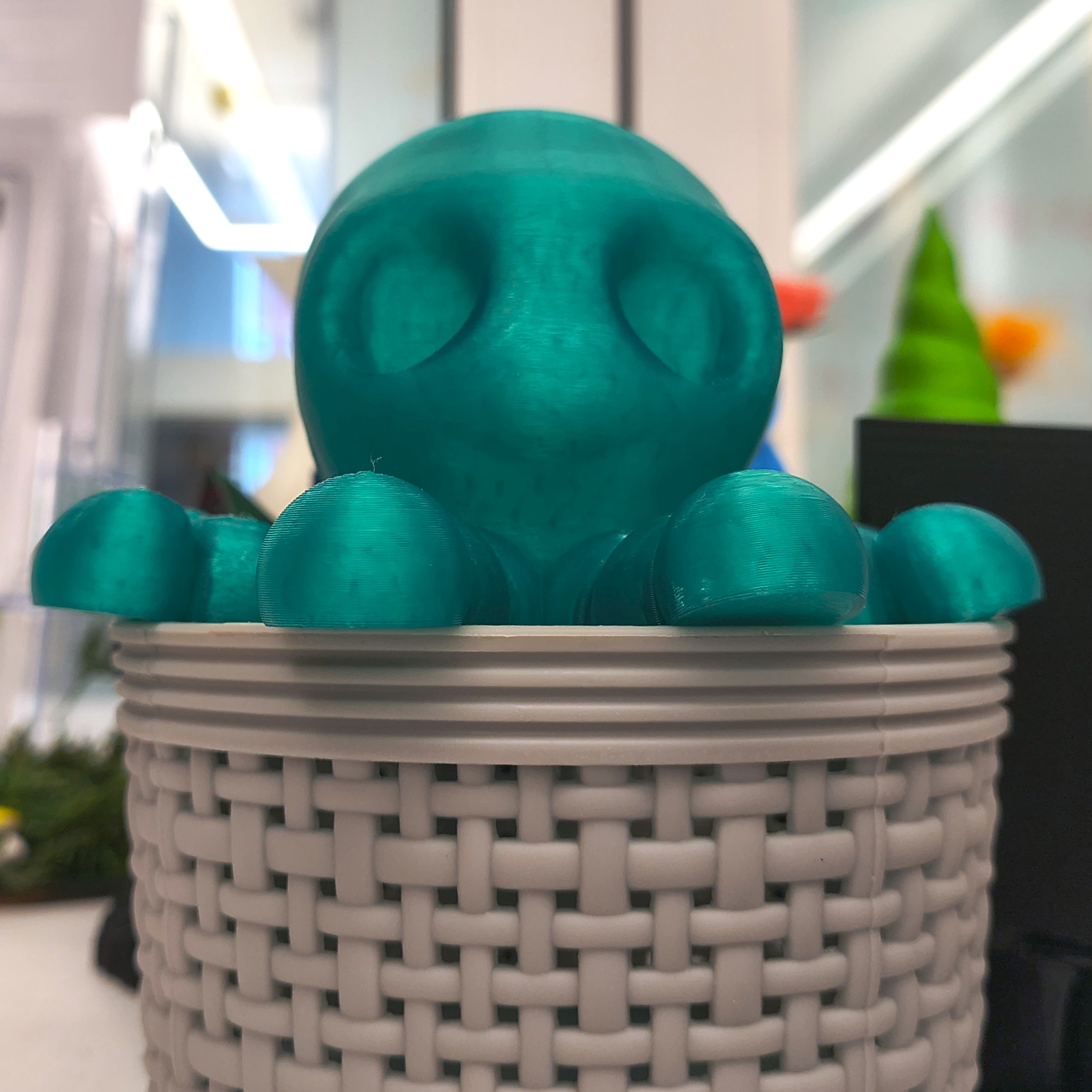 close-up photograph of a teal colored 3D printed creature that looks sort of like an octopus