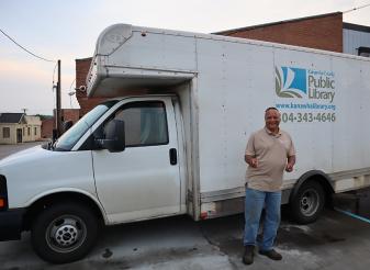 Gary Turpin stands in front of the white KCPL courier truck at Dunbar Branch, giving the thumbs up