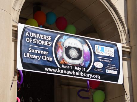 Library banner in arch with balloons at street fair