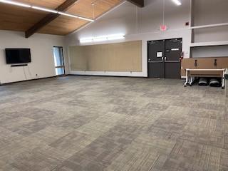 Dunbar Meeting Room, large room with gable ceiling, sound control panels, wall-mounted television, and available tables with chairs.