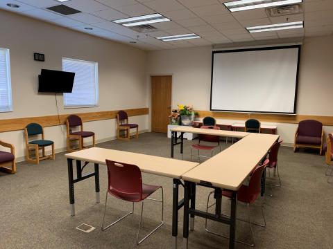 Sissonville Meeting Room, complete with tables and chairs, digital display, projection screen, and more