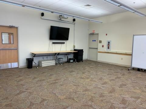 Meeting Room A with wall mounted HDTV, speakers and mobile table