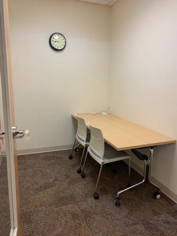 Study room with ADA height table and two chairs on wheels.