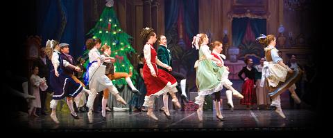 Various dancers depicting a scene from the holiday ballet, The Nutcracker, with a Christmas tree in the background