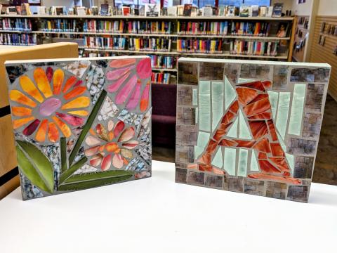 two square mosaic tiles, one with flowers and one with monogram letter A