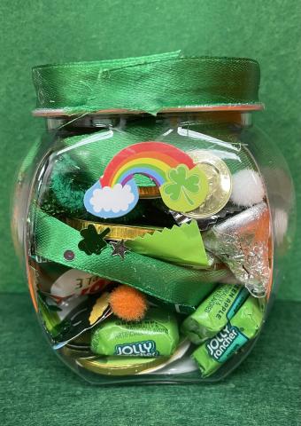 Small clear jar filled with candy, green background, rainbow