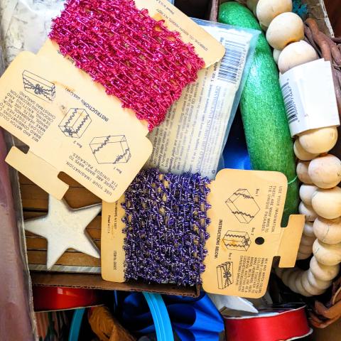 a box of colorful craft supplies, ribbon, wreath forms, and wooden beads