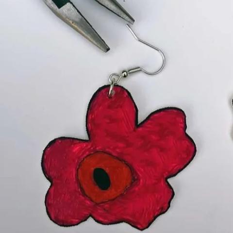 a close-up photo of an red earring shaped like a flower