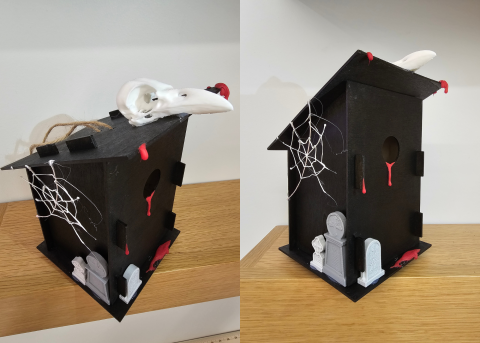 Two side-by-side images of a regtangular wooden birdhouse, painted black and adorned with a white 3D-printed bird skull, white 3D-penned spiderweb, red painted blood drops of hot glue, and 3D printed gray headstones.