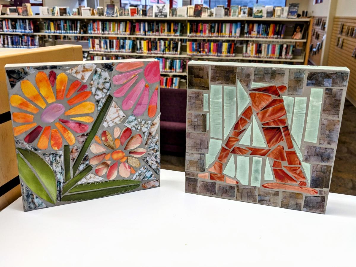 two square mosaic tiles, one with flowers and one with monogram letter A