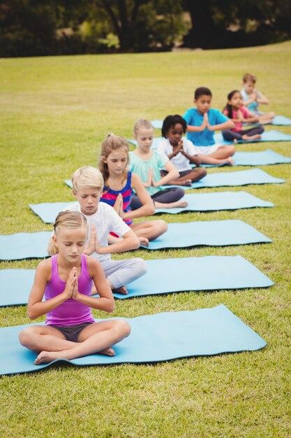 Outdoor scene with row of eight children doing yoga