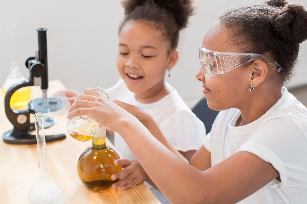 Two girls wearing googles holding glass beakers