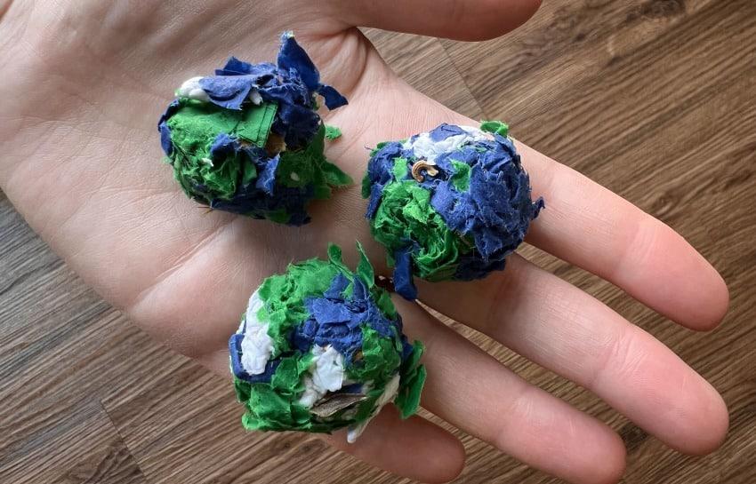 Blue, Green, and White Balls with seeds being held in a hand